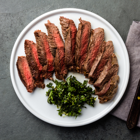 Das Bild präsentiert einen weißen Teller mit einem köstlichen, in Streifen geschnittenen Steak und Beilage.